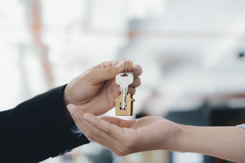 Immobilienmakler mit Schlüssel und Hausanhänger – Wohnungsübergabe