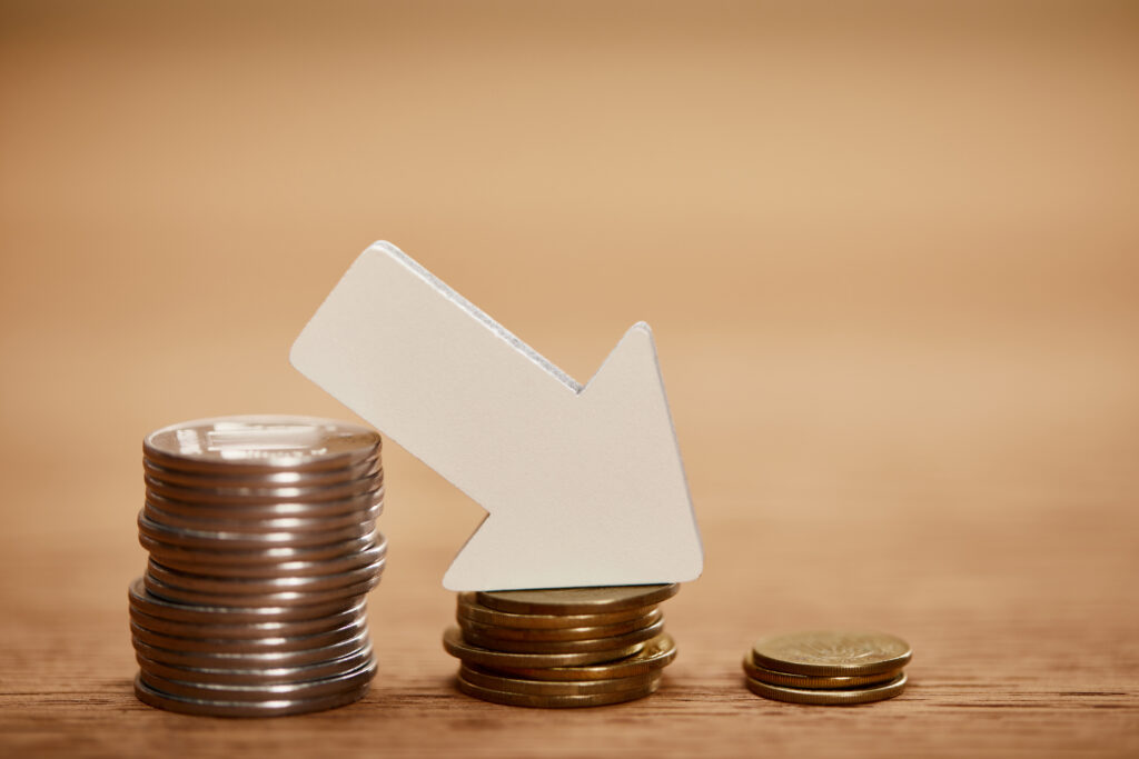 Sinkende Münzstapel – Immobilienpreise und Zinsentwicklung