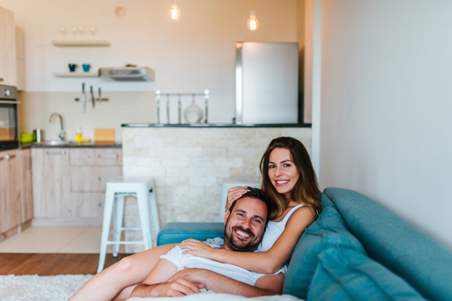 Junges Paar auf Sofa – zufriedene Immobilienkäufer